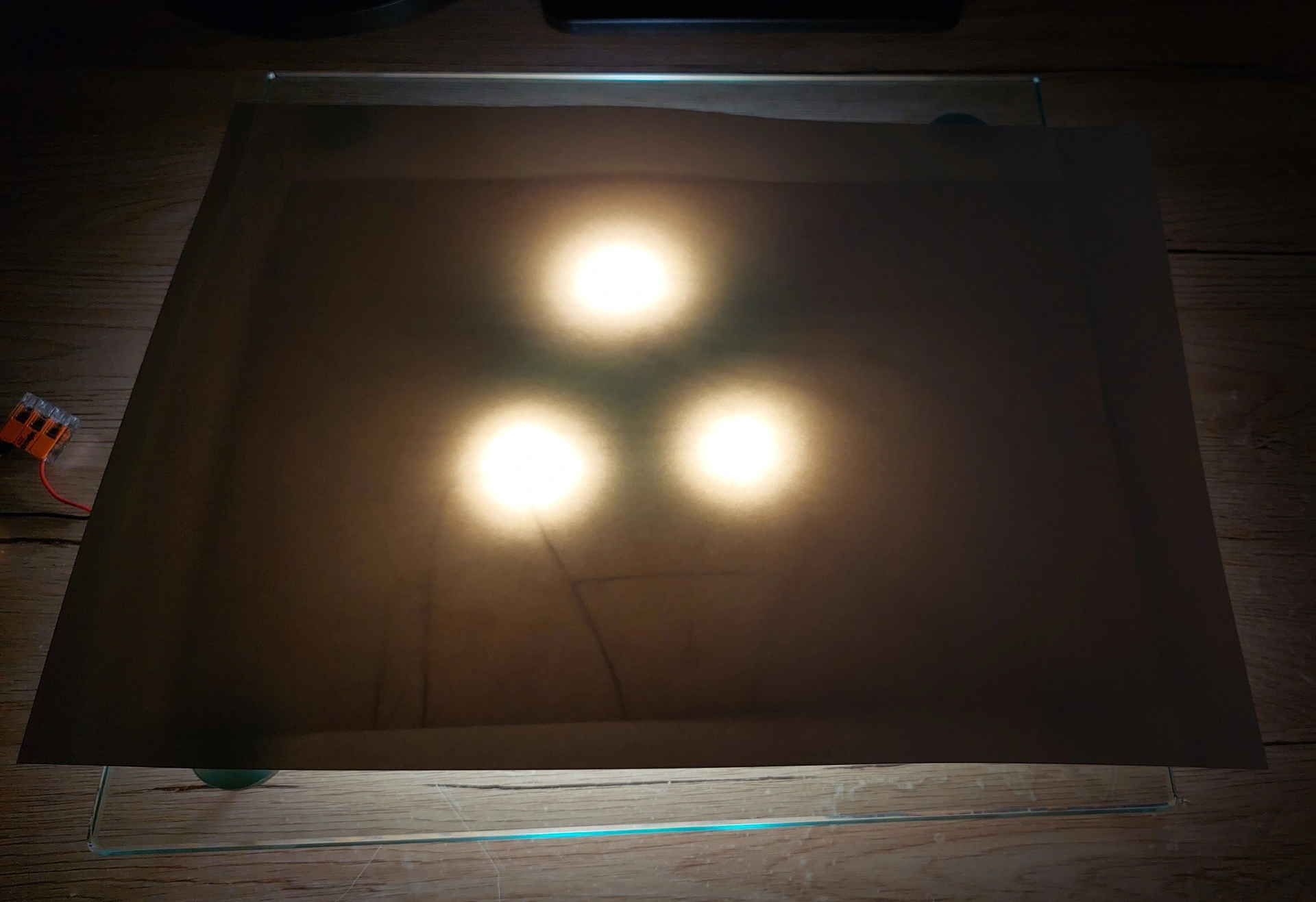 The complete DIY light box setup in action, with the LED lamp illuminating a sketch through the glass and a final paper placed on top for tracing.