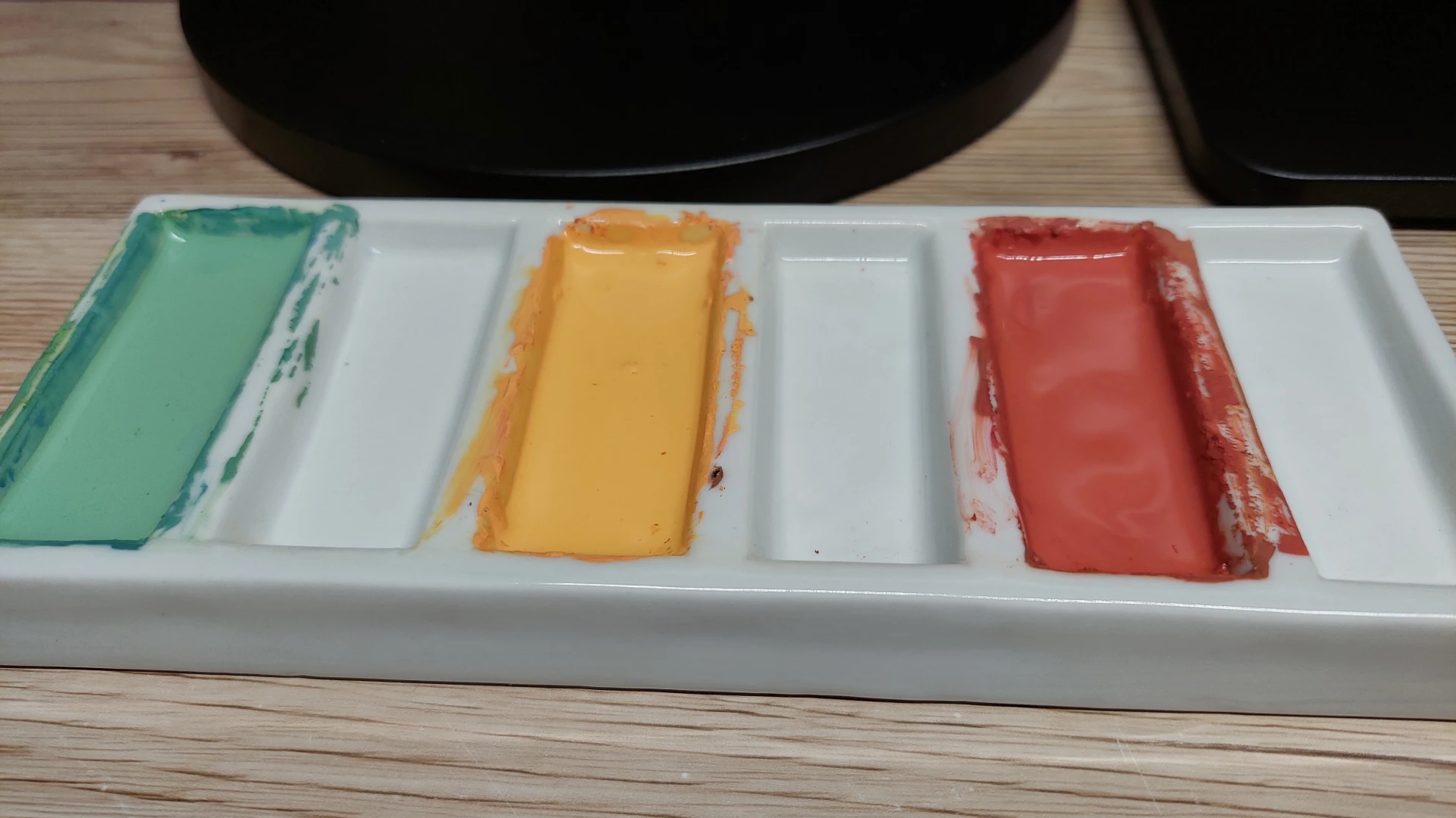 A porcelain mixing palette showing three custom gouache colors mixed for the sky.